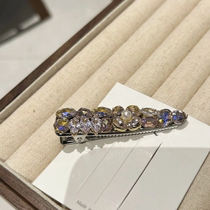 Close-up of a rhinestone duckbill hair clip with crystal flowers and a center pearl