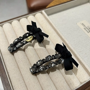 Detailed view of luxury ribbon bow hair clips with rhinestones and Lucky gold metal tag