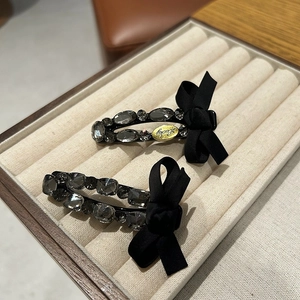 Detail of luxury rhinestone hair clips with black satin bows and Lucky engraving