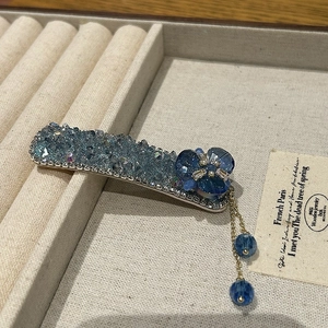 Pince à cheveux étincelante avec strass bleus, motif fleur et détails dorés