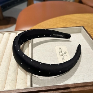 Elegant black satin sponge headband with rhinestones on a beige jewelry display tray