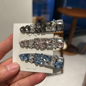 Close-up of three sparkling rhinestone hair clips in silver finish with various crystal shapes