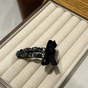 Detail of luxury rhinestone hair clip with grey crystals and black silk ribbon bow
