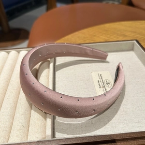 Close-up of pink satin padded headband with rhinestone embellishments in a jewelry box