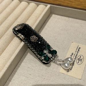 Macro detail of vintage emerald crystal hair clip with golden bee and rose flower carving