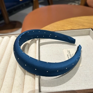 Detailed view of deep blue satin headband with sparkling rhinestones in a display box