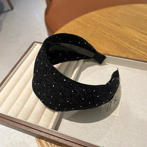 Gros plan détaillé d'un serre-tête noir large orné de strass brillants sur un plateau