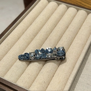 Detail of luxury hair clip featuring blue gemstones and crystals in star and heart shapes