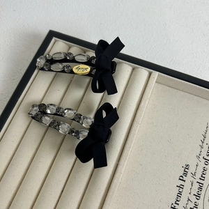 Detailed macro view of black ribbon bow hair clips with luxury sparkling rhinestones