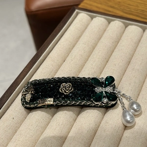 Detail of vintage flower hair clip with emerald rhinestones and golden bee motif