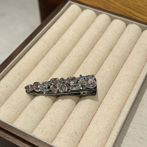 Detail of pink crystal hair clip with multi-shape rhinestones on a jewelry tray