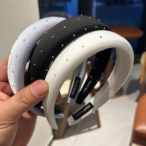 Close-up of three padded satin headbands with rhinestones in blue, black, and white