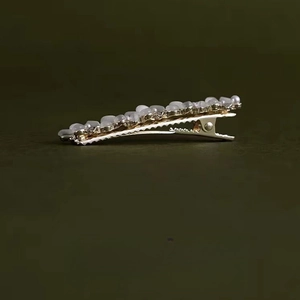 Nahaufnahme der goldfarbenen Haarspange mit Katzenaugen-Opalsteinen und Weizenähren-Detail