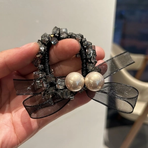 Detailansicht eines eleganten Haargummis mit Organza-Schleife, Perlen und Kristallen