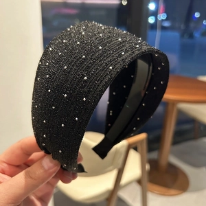 Gros plan sur un serre-tête large noir orné de strass scintillants dans un café