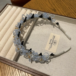 Détail d'un serre-tête floral fait main avec cristaux bleus et texture en soie
