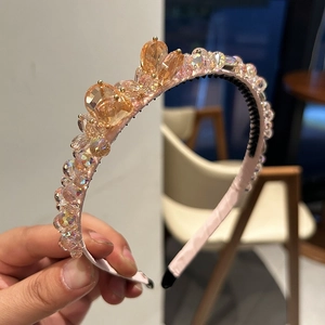 Gros plan sur un serre-tête en satin rose avec cristaux de champagne et dents antidérapantes