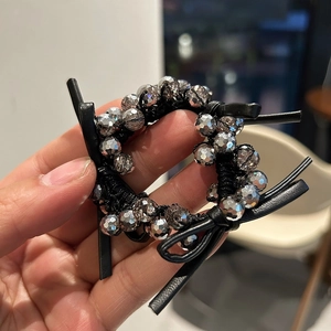 Close-up of black elastic hair tie with silver beaded details and faux leather bow accent