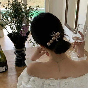 Barrette élégante avec perles champagne et nœud en ruban sur une coiffure en chignon