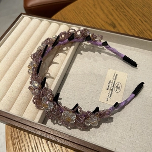 Détail du serre-tête perlé violet avec motifs floraux et peigne de maintien noir intégré
