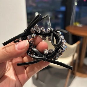 Detailed view of elastic hair tie with black leather bows and faceted crystal beads