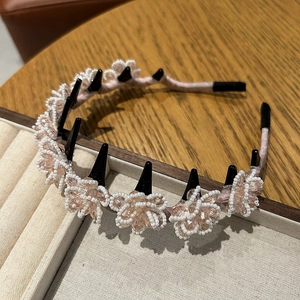 Detail of pink satin headband featuring crystal flower clips on a velvet jewelry tray