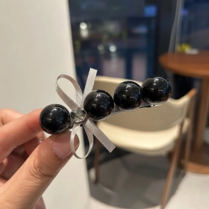 Vue détaillée d'une barrette en perles noires avec un élégant nœud et un strass brillant