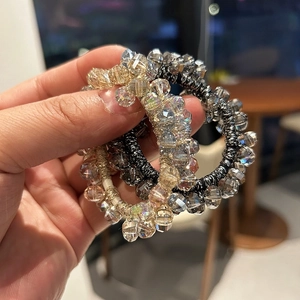 Handheld view of shimmering gradient crystal bead elastic hair ties in various colors