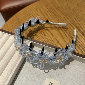 Détail d'un serre-tête fleurs en cristal bleu avec dents antidérapantes et perles fines