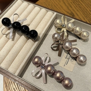 Détail de barrettes à perles et rubans en quatre couleurs sur un plateau de velours