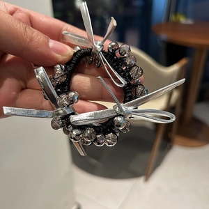 Detailed shot of black beaded hair tie with grey crystal beads and silver bow charm