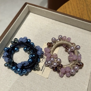 Dettaglio di elastici per capelli di lusso con perline di cristallo blu e viola fini