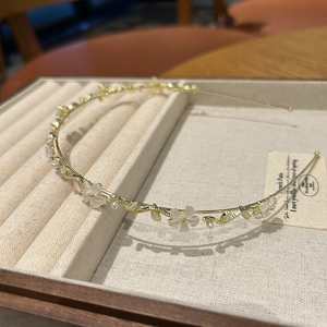 Détail d'un serre-tête doré avec fleurs blanches et perles fines sur un présentoir