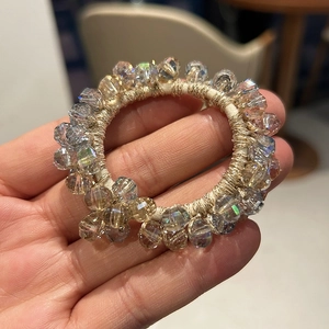Detailed macro view of handmade gradient crystal beads hair tie with golden wire threads