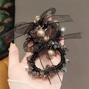 Detailaufnahme von schwarzem Haargummi mit Netzschleife, Perlen und Glitzersteinen