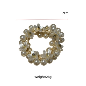 Detail view of a 7cm pearl hair tie with white camellia flower and weight scale mark