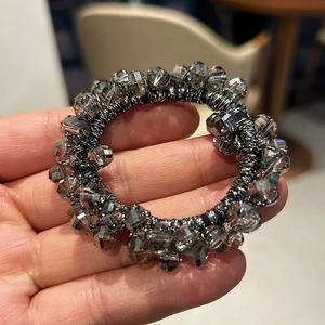 Detailed macro view of multifaceted grey crystal beads on an elastic hair tie band