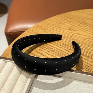 Detailed view of black satin sponge headband with silver rhinestones on wooden surface