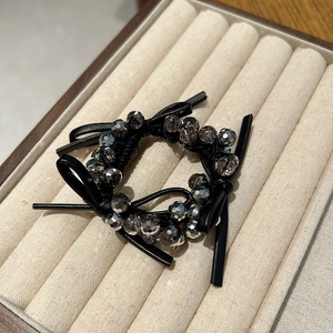 Elegant black beaded hair tie with leather bow and grey crystal beads on velvet
