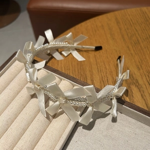 Detailed view of pearl beaded headband with cream satin bows on a jewelry stand