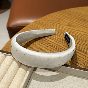 Detail of white satin padded headband with silver studs and handmade label