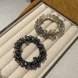 Detail of crystal bead hair ties in black and champagne on a velvet display box
