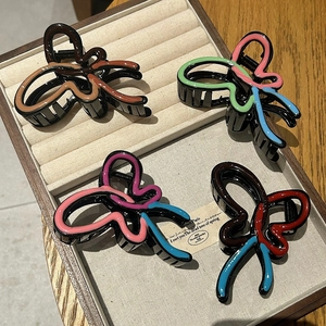 Set mit vier Schmetterlings-Haarklammern aus buntem Harz auf einem beigen Schmuck-Display