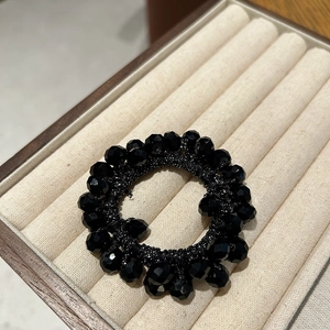 Detail of a black crystal beaded hair tie displayed in a jewelry box with multi-faceted beads