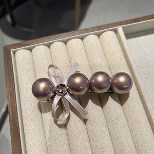 Détail de la barrette à perles lavande et nœud en ruban avec un strass étincelant