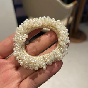 Detailed macro view of elastic hair tie with dense white faux pearls and mesh texture