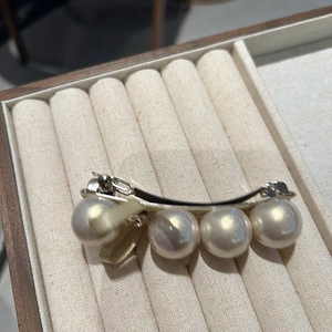 Détail de quatre grandes perles fantaisie et un nœud en soie beige sur une barrette