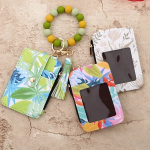 Detail view of floral card holder wallet with silicone bead wristlet and tassel keychain
