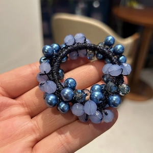 Dettaglio di perle di cristallo intrecciate di lusso su elastico nero tenuto in mano
