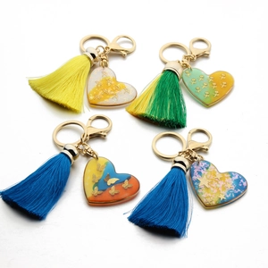 Detail of four handmade resin heart keychains with colorful tassels and gold lobster clasps